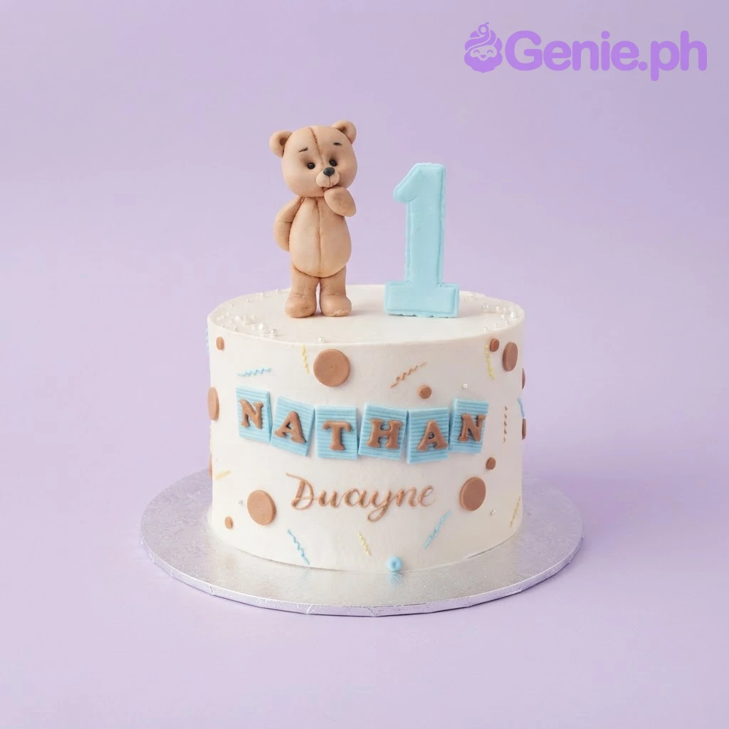 Teddy Bear White Birthday Cake White 1-tier birthday cake with smooth soft icing, a teddy bear topper, number one, and blue name plaques