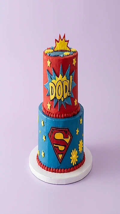 Red and blue 2-tier superhero cake with Superman logo and yellow stars