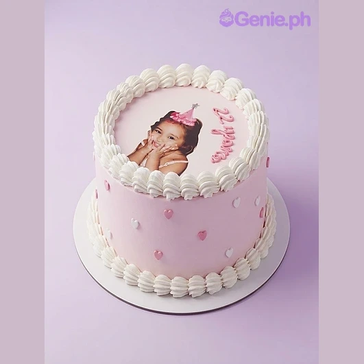 Photo White Heart Birthday Cake White 1-tier soft icing cake with a large edible photo print of a child, pink piped text, and small pink heart accents