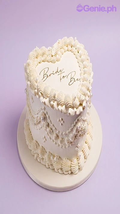 Bride To Be White Heart Cake White heart-shaped cake with soft icing, piped borders, pearl accents, and a Bride to Be printout topper