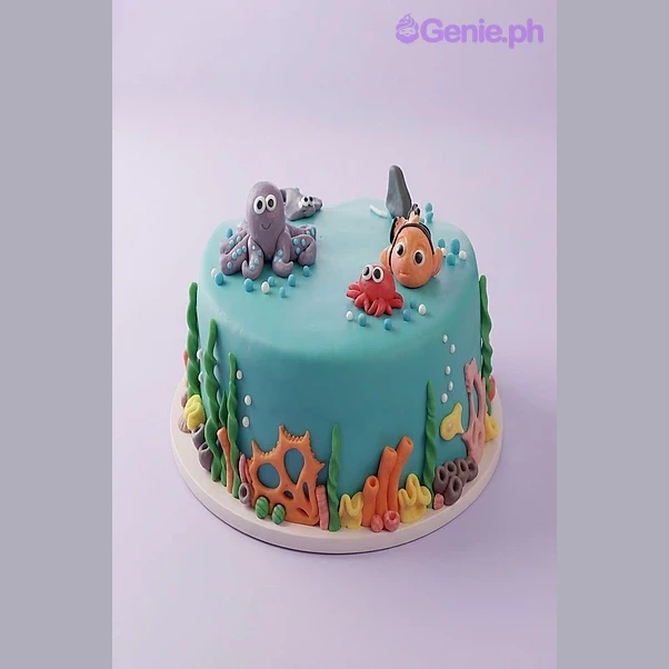 Under The Sea Teal Cake Teal 1-tier fondant cake with an octopus, clownfish, and crab topper, decorated with green seaweed and orange coral accents