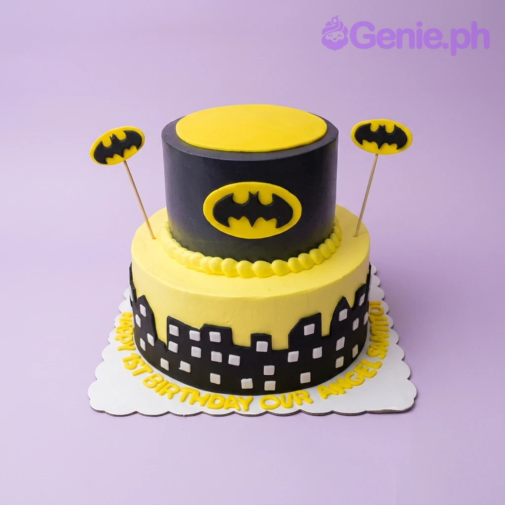 Batman-Inspired Silhouette 2-Tier Birthday Cake Two-tier Batman themed birthday cake with yellow and black icing, city skyline silhouette, and Batman logo toppers.