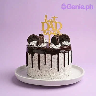 Best Dad Ever White Drip Cake A single-tier white cake with black cookie crumbs, chocolate drip, whipped cream dollops, Oreo cookies, and a gold Best Dad Ever topper.