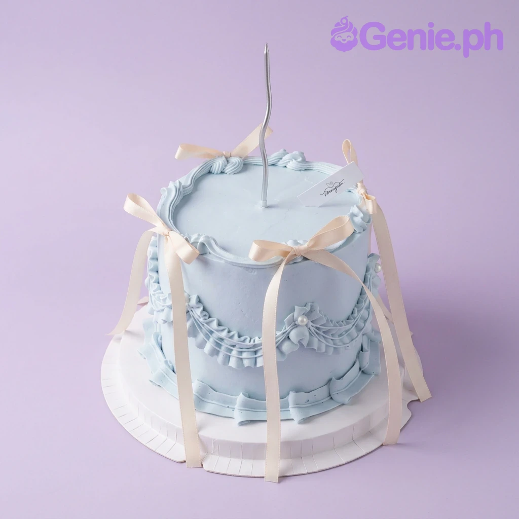 A light blue 1 Tier cake themed Blue Vintage, featuring a silver wavy candle, ruffles, swags, and cream ribbons.