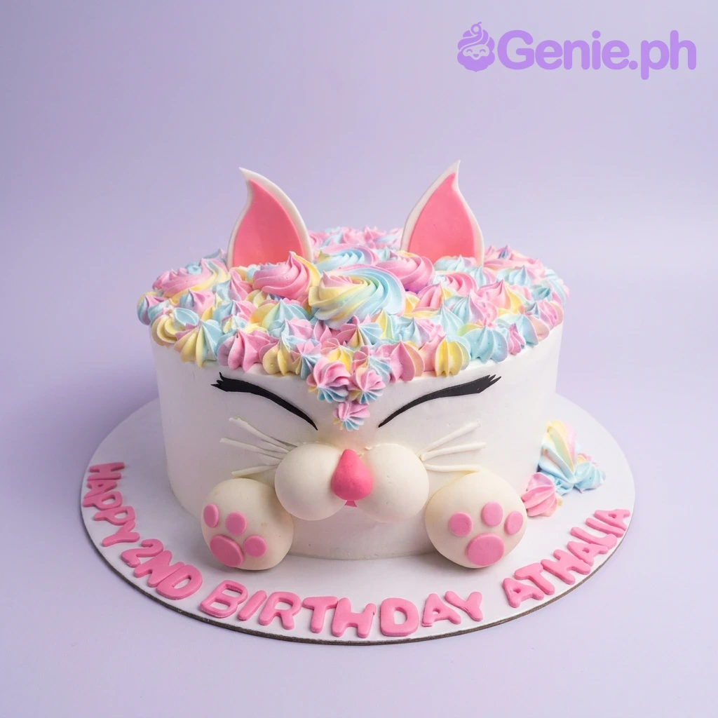 Cat White Birthday Cake White cat-themed birthday cake with colorful pastel icing swirls, fondant ears, paws, and a pink nose.