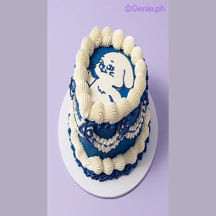 Character Birthday Cake Navy blue and white round cake with a piped icing character drawing on top and a shell border