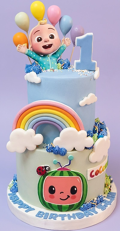 2-tier Cocomelon themed cake with JJ figure, rainbow, clouds, and watermelon logo