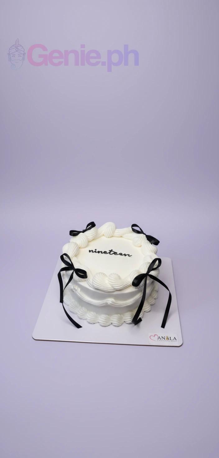 Minimalist white coquette cake with black satin ribbons and 'nineteen' piped in black icing.
