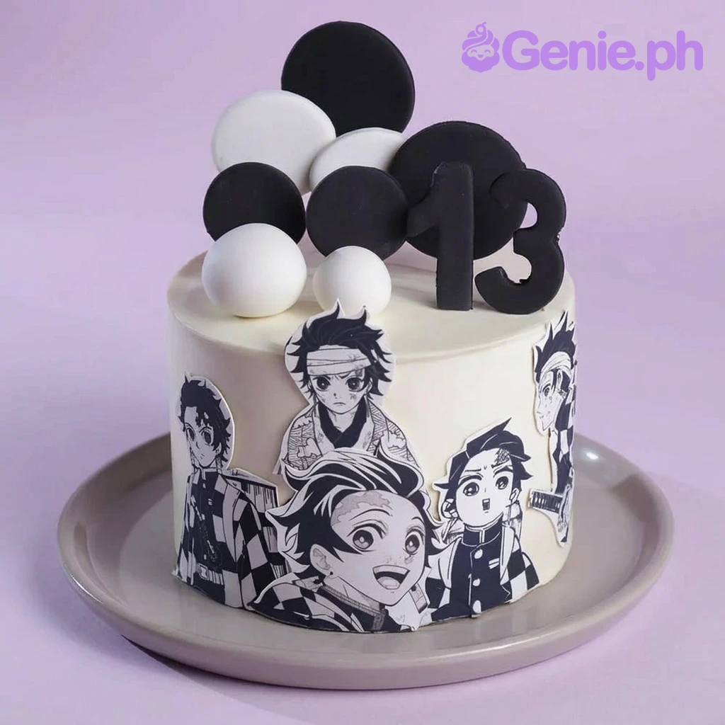 Demon Slayer-Inspired White Cake A white 1 tier cake featuring a black number 13, character cutouts of Tanjiro Kamado, black circular discs, and white fondant discs and spheres.