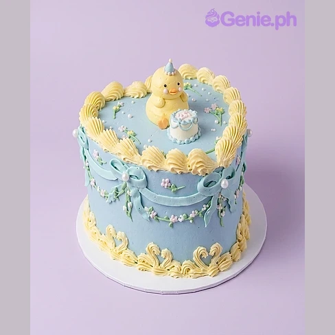Duck Heart Cake One tier cake with a yellow duck figurine and a mini cake topper, sky blue soft icing, piped yellow rosettes and white pearl dragees