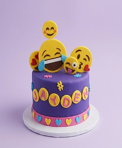 Purple fondant emoji cake with yellow emoji toppers and pink name letters Jayden