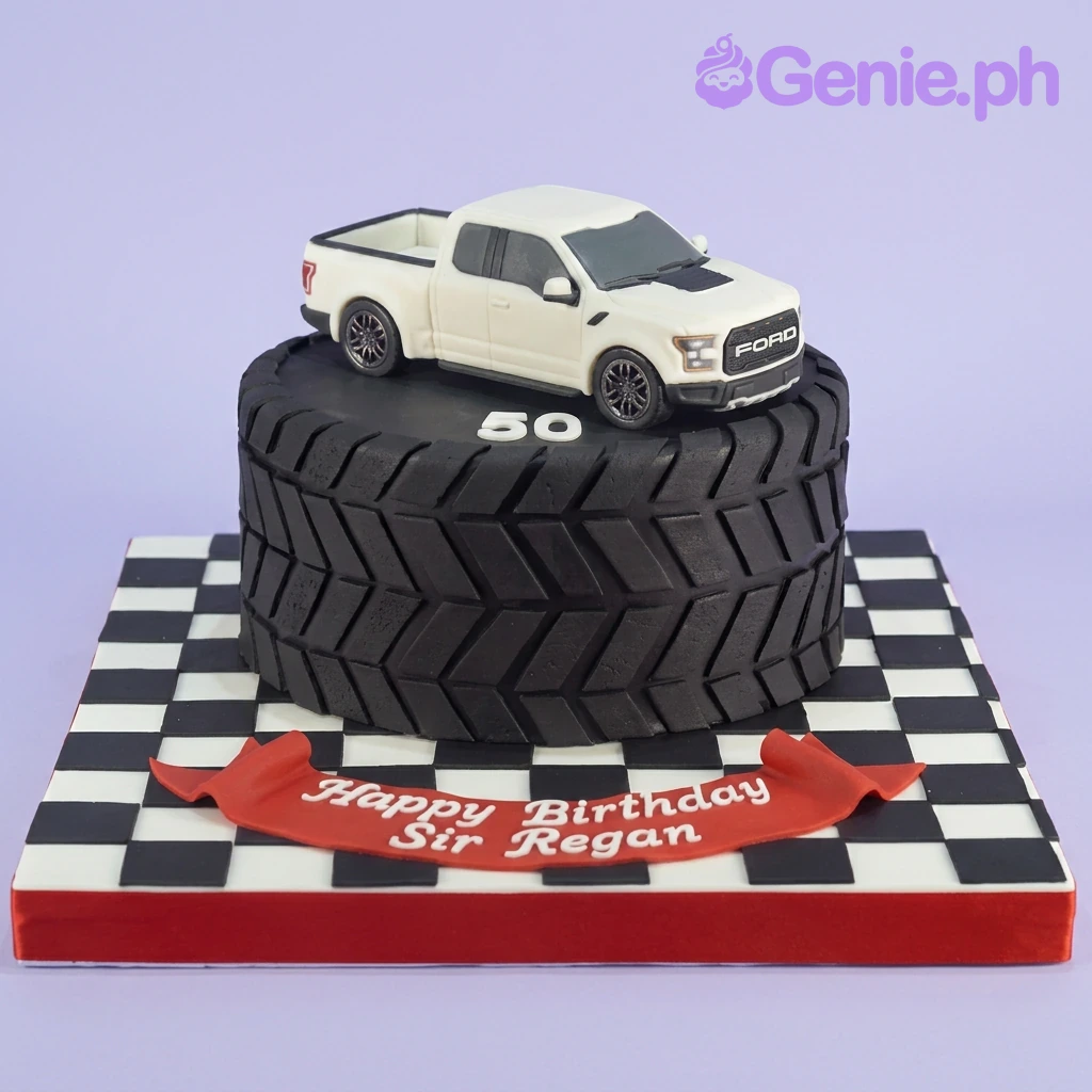Ford Raptor Tire Black Birthday Cake A black tire-shaped fondant cake with a white Ford Raptor toy truck, number 50, red banner, and checkered baseboard.