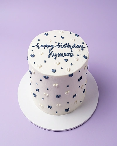 Heart cake scattered design — 1 layer soft icing cake in white — with scattered hearts and dots, and custom "happy birthday Kymani" message