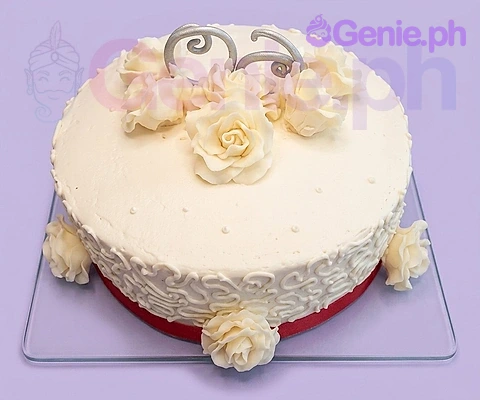 Ivory Rose Floral Anniversary Cake An ivory 1-Tier cake themed around Ivory Rose, featuring ivory gumpaste roses, silver scrolls, and a red ribbon base.