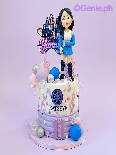 Katseye-Inspired Kpop Birthday Cake Purple and white Katseye themed birthday cake with a 3D girl figurine, musical notes, and blue and silver spheres.