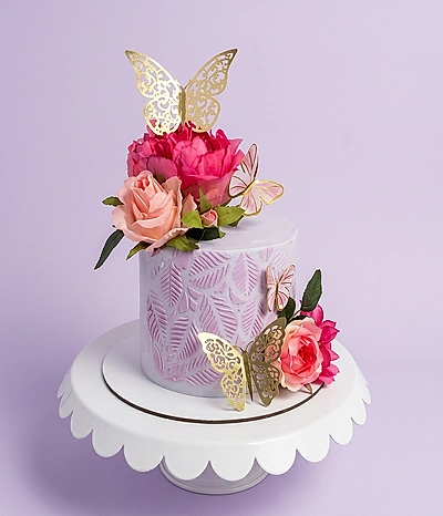 Lavender 1-tier cake with textured leaf patterns, pink roses, and gold butterfly toppers on a white scalloped stand.