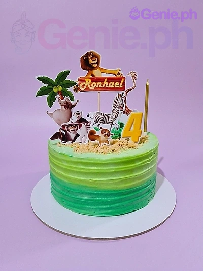 Madagascar-Inspired Mint Birthday Cake A green gradient 1-tier cake themed around Madagascar, featuring character printouts, a 'Ronhael' banner, and yellow candles.