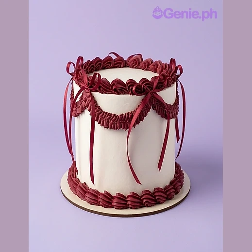 Minimalist Burgundy White Cake White single-tier cake with dark red piped borders, swags, and satin ribbon bows