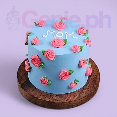 Light blue minimalist cake decorated with pink piped icing roses and green leaves with a white icing message saying MOM on top. Light blue minimalist cake decorated with pink piped icing roses and green leaves with a white icing message saying MOM on top.
