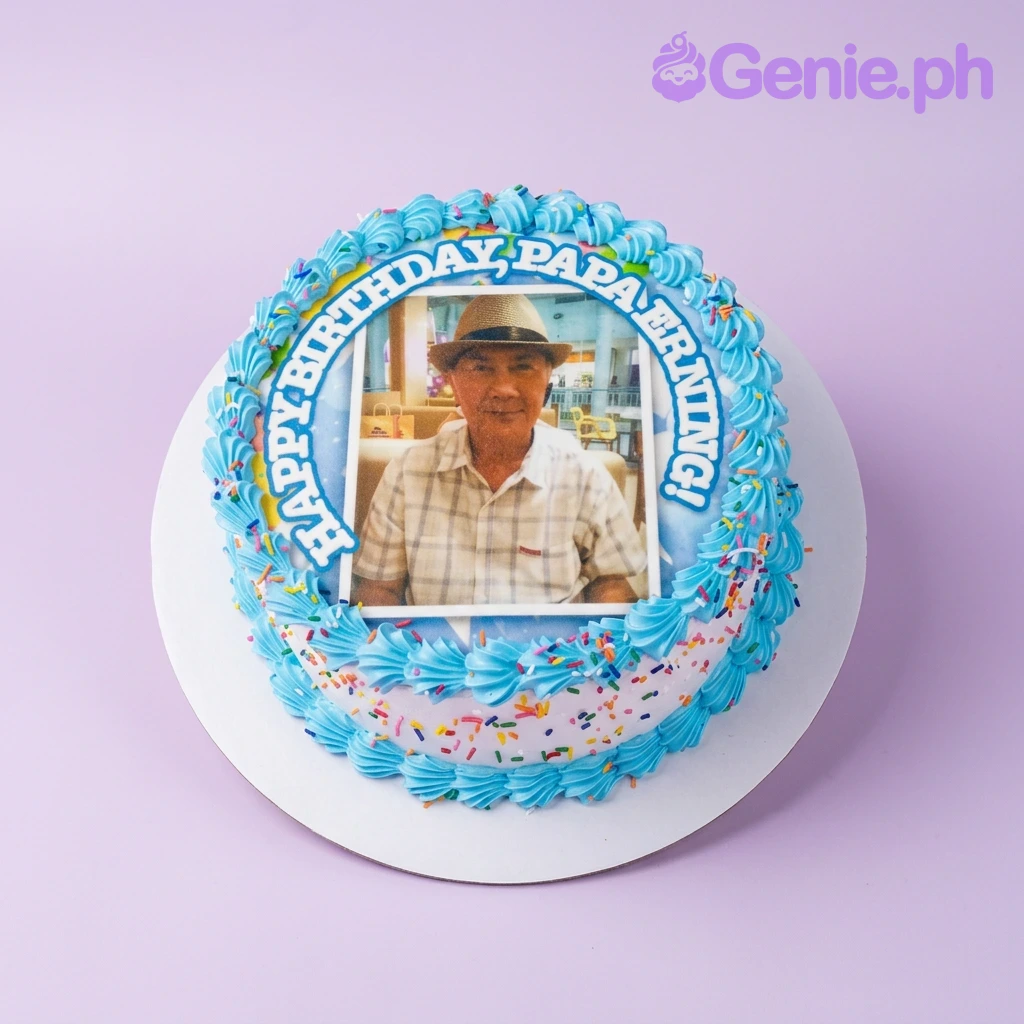 Papa Erning Photo White Birthday Cake A white and blue 1-tier cake for Papa Erning, featuring a large photo printout of a man, blue icing rosettes, and colorful sprinkles.