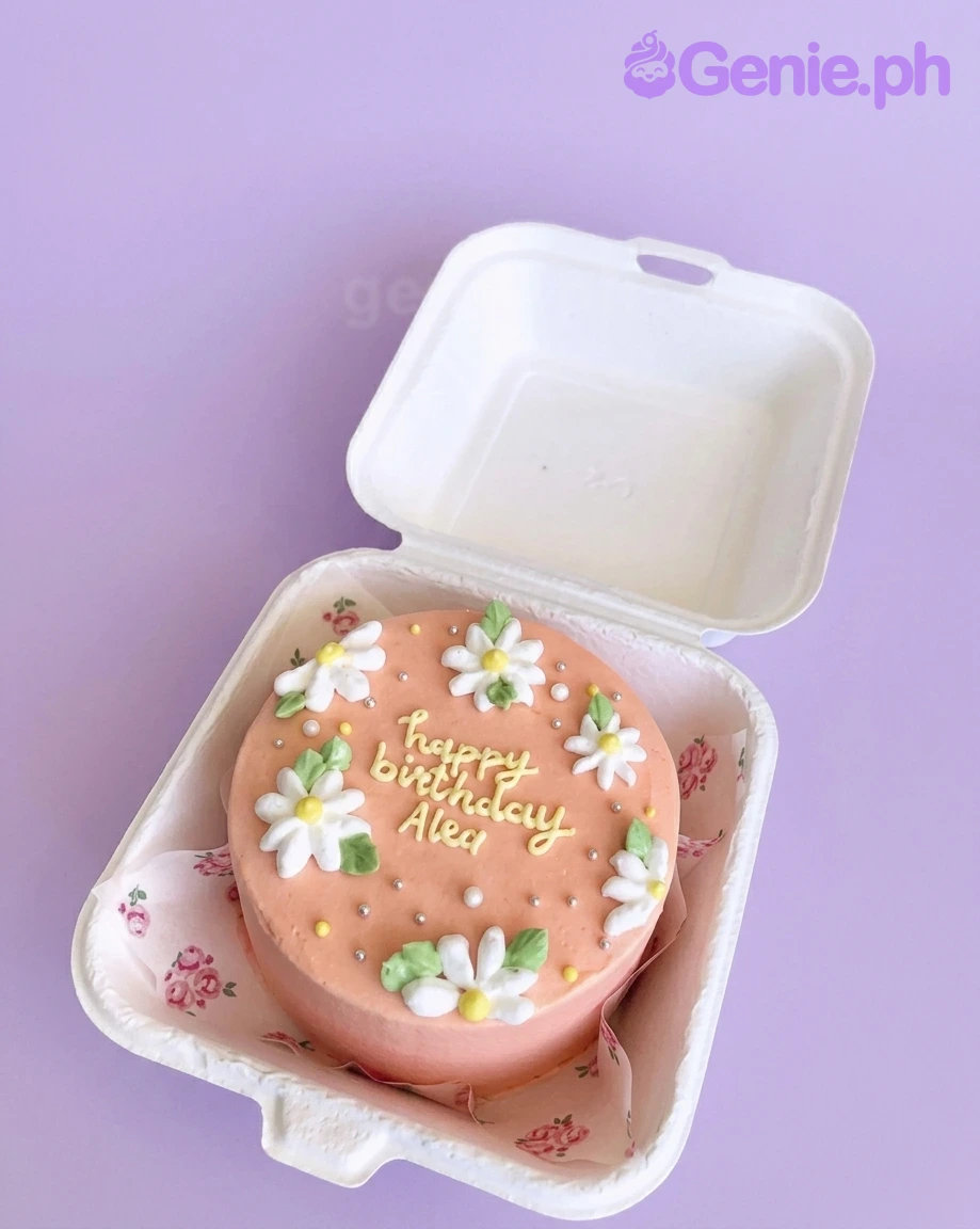 Peach Daisy Bento Floral Birthday Cake A peach Bento cake with white and yellow icing daisies, silver dragees, and 'happy birthday Alex' text.