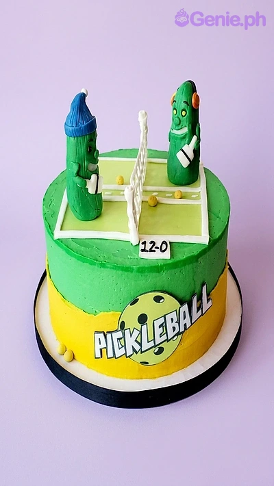 Pickleball Birthday Cake A green and yellow 1 Tier cake themed around Pickleball, featuring 3D fondant pickle characters playing on a court with a net.
