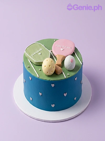 Pickleball Birthday Cake Light green and blue single tier cake with pink and green pickleball paddles and balls