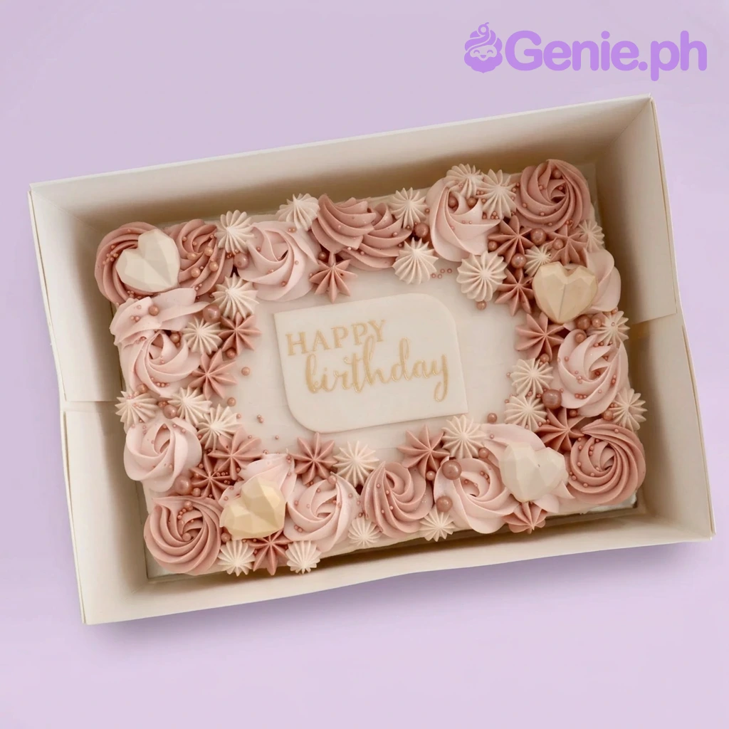 A rectangular cake with pink and tan rosettes, geometric chocolate hearts, and a 'Happy Birthday' plaque.