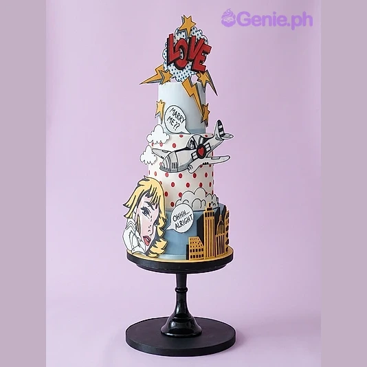 Pop Art Comic Heart 3-Tier Cake Light blue 3-tier fondant cake with pop art comic book theme featuring a plane, city skyline, and speech bubbles
