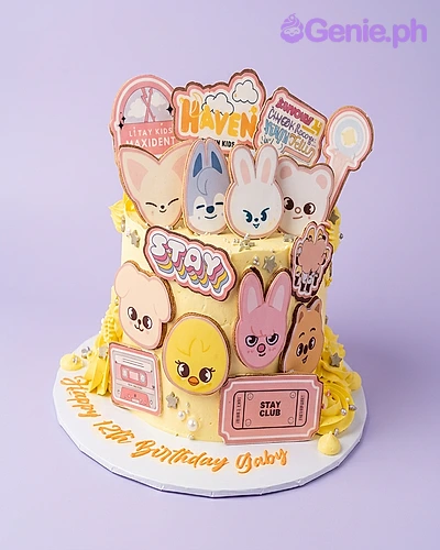 Stray Kids Ivory 2-Tier Cake Two-tier ivory cake with Stray Kids character faces, logos, and text cutouts, piped icing rosettes, and silver star sprinkles