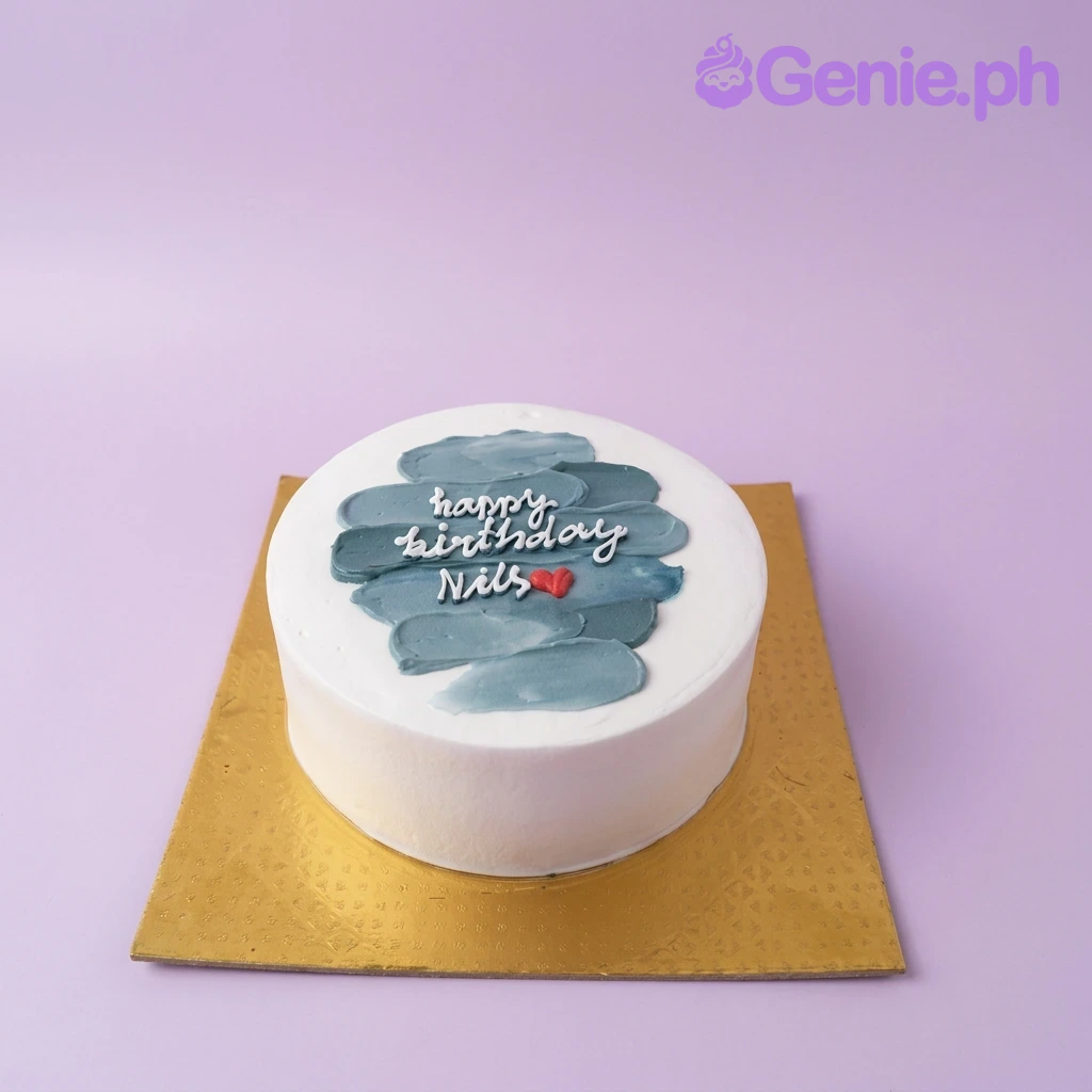 A white and teal 1-tier minimalist cake, featuring a textured teal icing center, white 'Happy Birthday Nils' text, and a red heart.