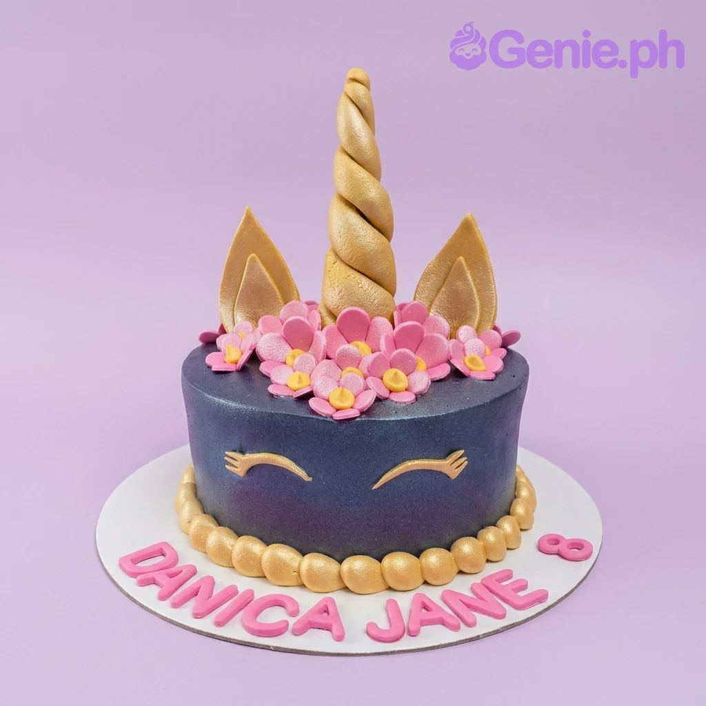 A navy blue 1 Tier unicorn cake, featuring a gold horn, ears, pink fondant flowers, gold eyelashes, and 'DANICA JANE 8' on a white base.