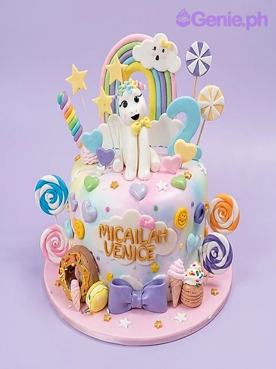 Unicorn Rainbow Pink Birthday Cake A colorful 1-tier fondant unicorn rainbow cake, featuring a white pony, rainbow, number two, and lollipops.