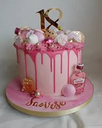 Pink drip cake with a gold number 18 topper, pink gin bottle, and assorted pink and white meringue and chocolate decorations. Pink drip cake with a gold number 18 topper, pink gin bottle, and assorted pink and white meringue and chocolate decorations.