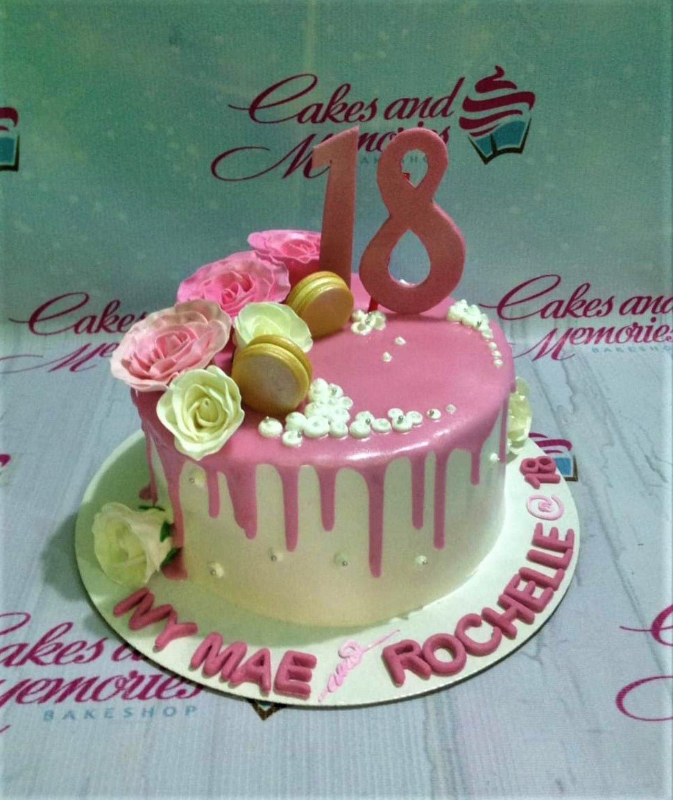 Pink and white 18th birthday cake with pink drip, edible roses, macarons, and a large pink number 18 topper. Pink and white 18th birthday cake with pink drip, edible roses, macarons, and a large pink number 18 topper.