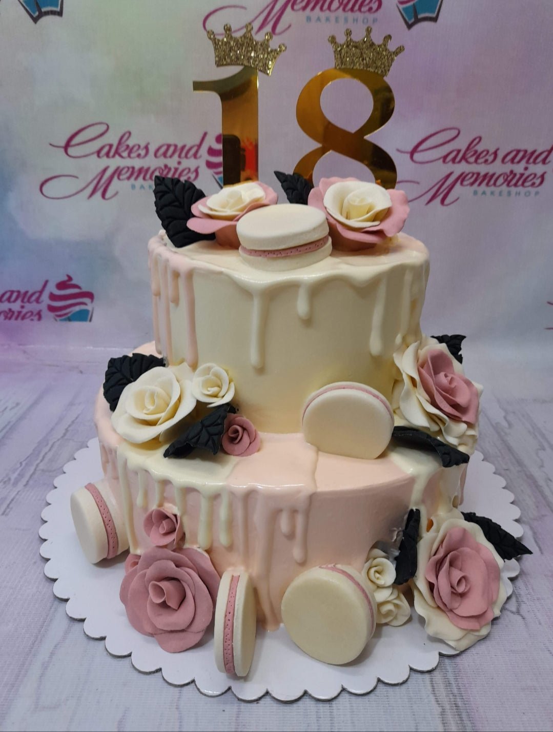 Two-tier pink and cream 18th birthday cake with gold number 18 toppers, macarons, and fondant roses. Two-tier pink and cream 18th birthday cake with gold number 18 toppers, macarons, and fondant roses.