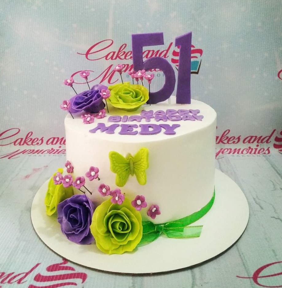 White round cake with purple and lime green fondant roses, a green butterfly, and a purple number 51 topper. White round cake with purple and lime green fondant roses, a green butterfly, and a purple number 51 topper.