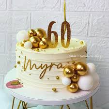 White 1-tier birthday cake with horizontal icing ridges, gold and white spheres, and a gold glitter number 60 topper. White 1-tier birthday cake with horizontal icing ridges, gold and white spheres, and a gold glitter number 60 topper.