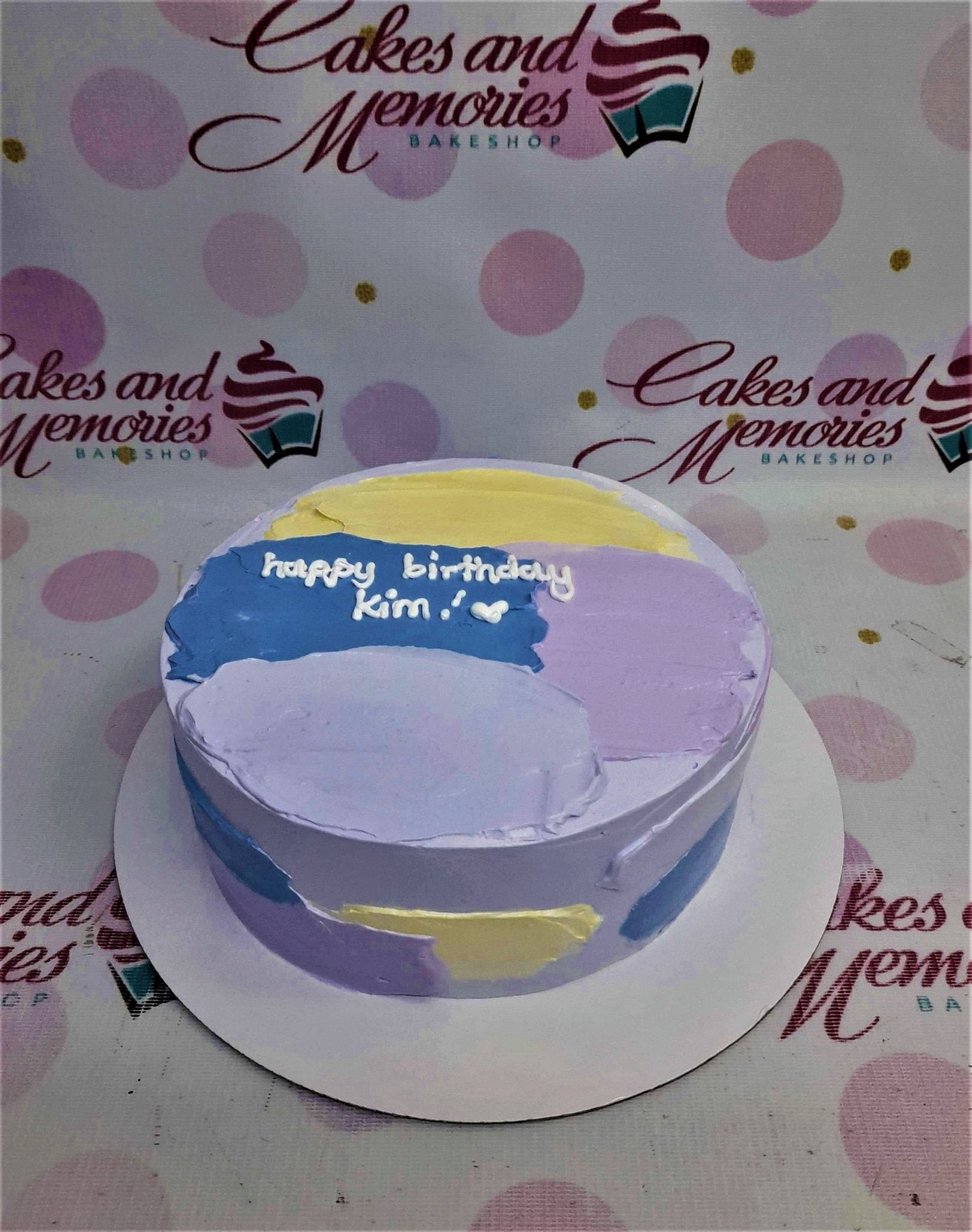 Bento cake with abstract palette knife icing in purple, blue, and yellow with a white birthday message.