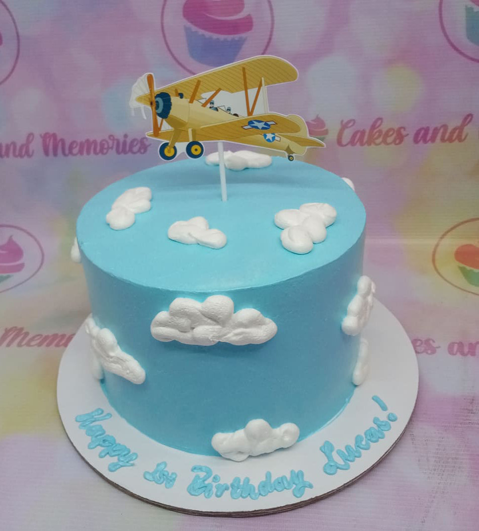 Light blue sky themed cake with white fondant clouds and a yellow biplane printout topper. Light blue sky themed cake with white fondant clouds and a yellow biplane printout topper.