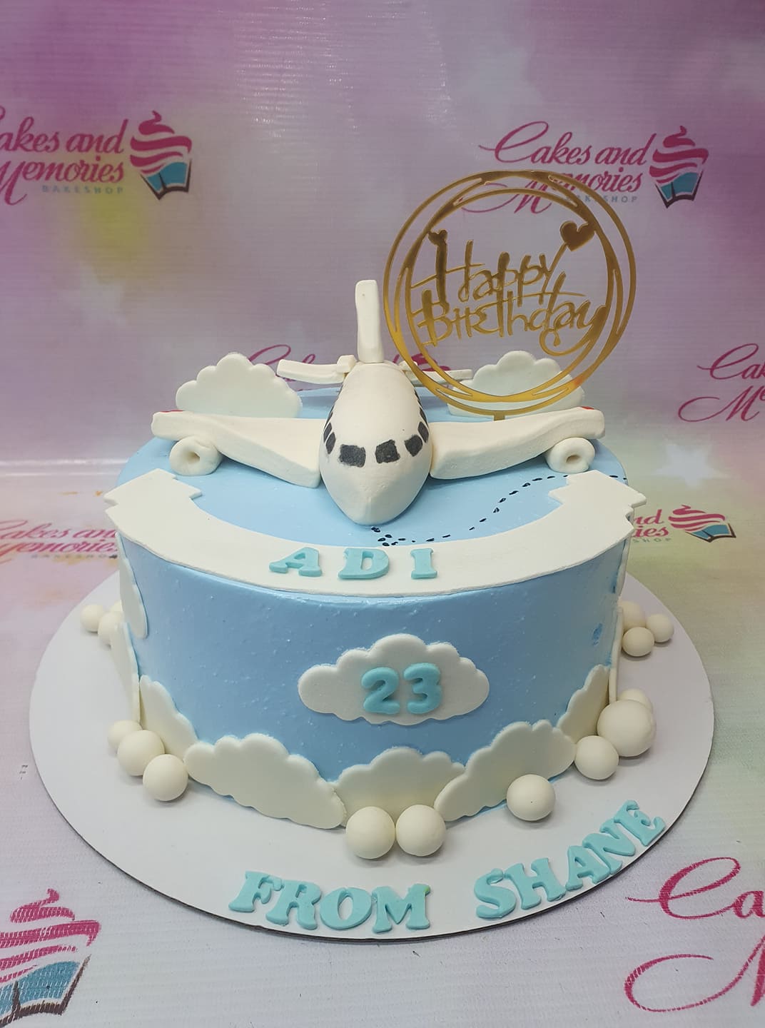 Light blue airplane themed birthday cake with white fondant clouds and a gold Happy Birthday topper. Light blue airplane themed birthday cake with white fondant clouds and a gold Happy Birthday topper.