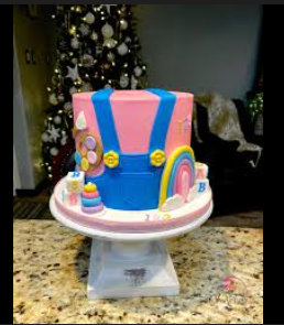 Pink fondant cake designed like a pair of blue overalls with a rainbow, building blocks, and art palette decorations. Pink fondant cake designed like a pair of blue overalls with a rainbow, building blocks, and art palette decorations.