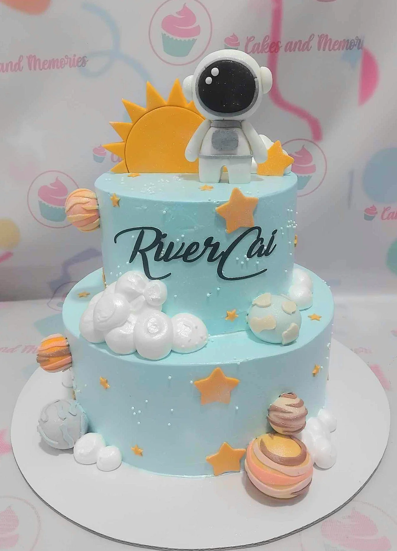 Two-tier light blue space themed cake with a 3D fondant astronaut, sun, planets, and stars. Two-tier light blue space themed cake with a 3D fondant astronaut, sun, planets, and stars.