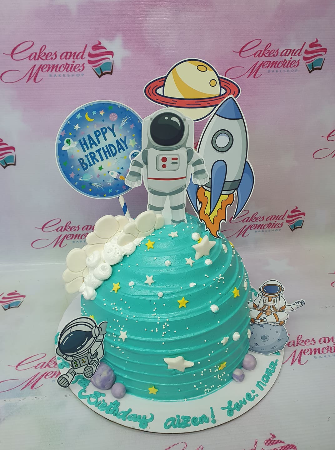 Teal space themed birthday cake with astronaut, rocket, and planet toppers, white fondant clouds, and yellow stars. Teal space themed birthday cake with astronaut, rocket, and planet toppers, white fondant clouds, and yellow stars.