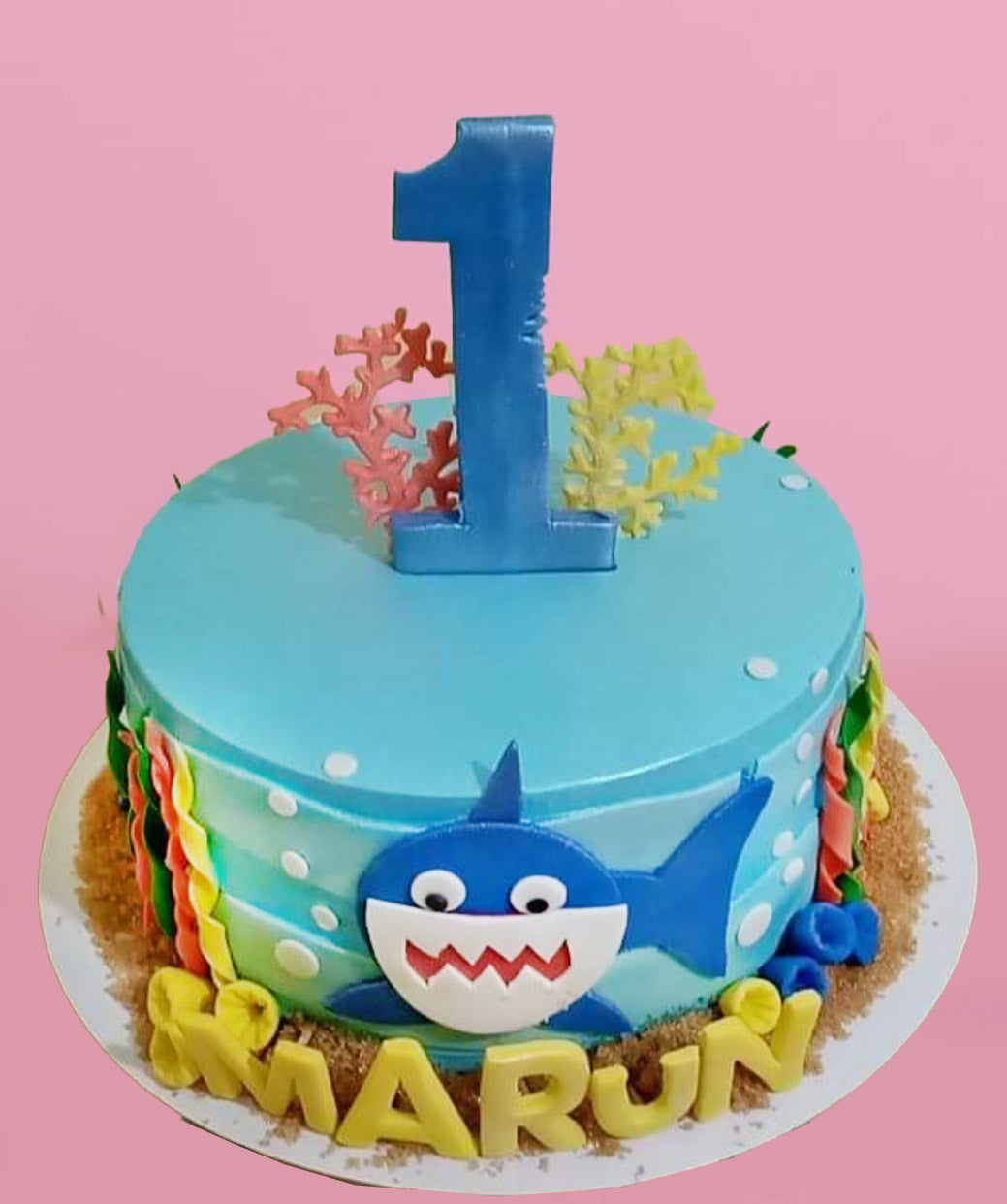 Blue Baby Shark themed birthday cake with a large blue number one topper and fondant sea life decorations. Blue Baby Shark themed birthday cake with a large blue number one topper and fondant sea life decorations.