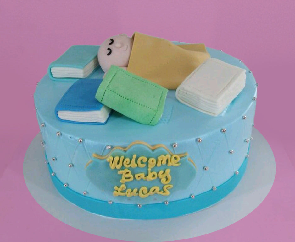 Light blue baby shower cake with fondant books and a sleeping baby figure on top, decorated with silver dragees and a welcome message. Light blue baby shower cake with fondant books and a sleeping baby figure on top, decorated with silver dragees and a welcome message.
