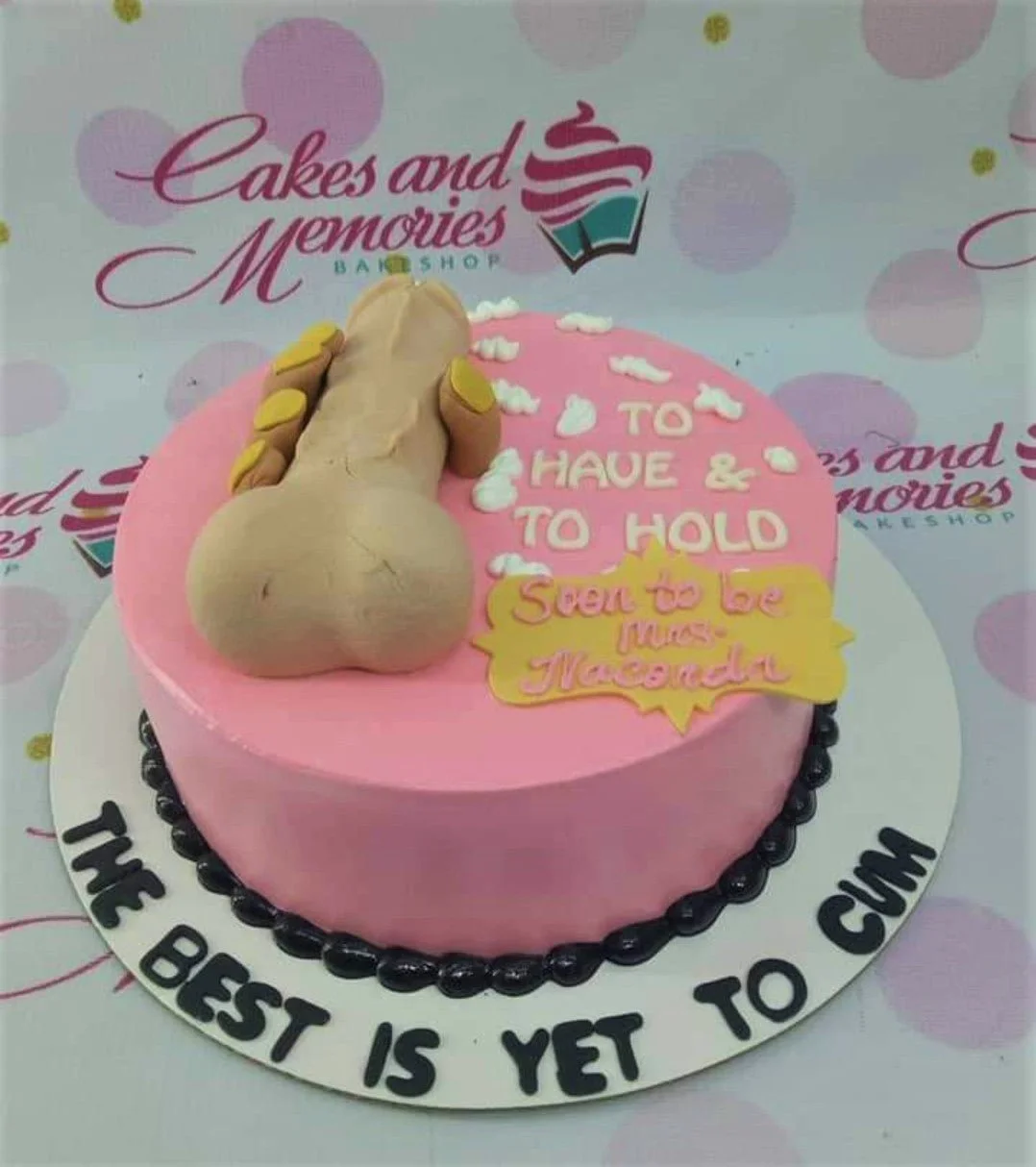 Bachelorette Pink Cake A pink 1-tier cake themed around Bachelorette, featuring a large tan fondant phallic topper, white icing dollops, and black piped border.