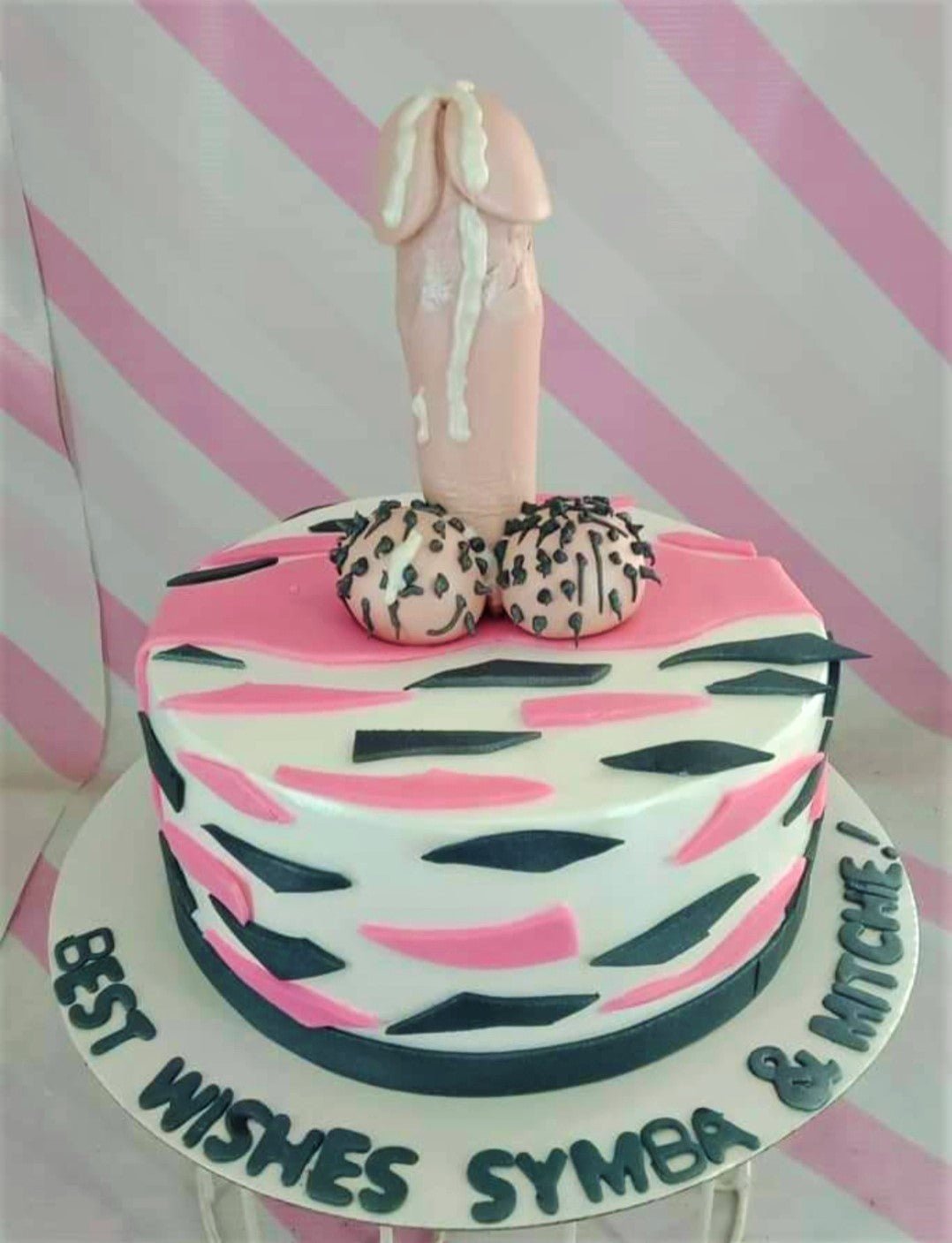 White fondant cake with pink and black zebra stripes featuring a large flesh-colored 3D fondant phallic topper with white icing drips. White fondant cake with pink and black zebra stripes featuring a large flesh-colored 3D fondant phallic topper with white icing drips.
