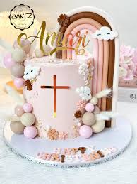 Pink baptism cake with a gold cross, rainbow topper, clouds, and pink and tan spheres. Pink baptism cake with a gold cross, rainbow topper, clouds, and pink and tan spheres.