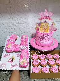 Pink Barbie themed birthday cake with a large Barbie printout topper and matching pink cupcakes arranged in the shape of the number four. Pink Barbie themed birthday cake with a large Barbie printout topper and matching pink cupcakes arranged in the shape of the number four.